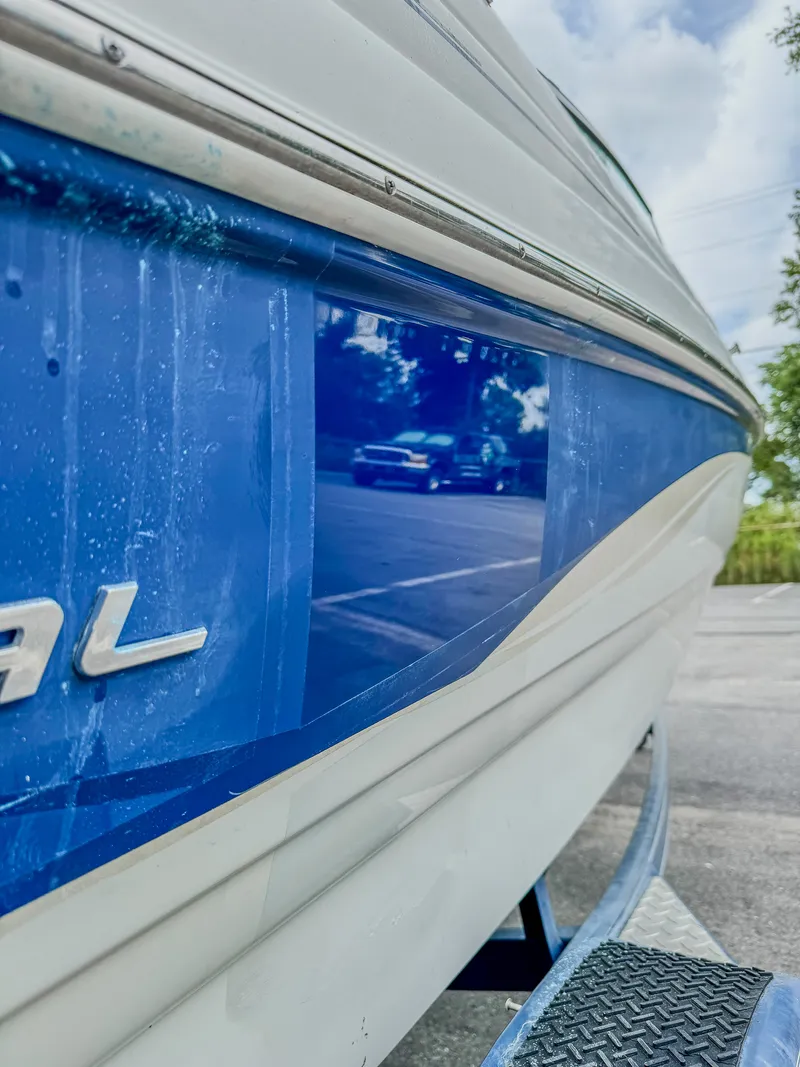 Correction test spot on a blue Chaparral hull showing restored gloss against oxidized gelcoat