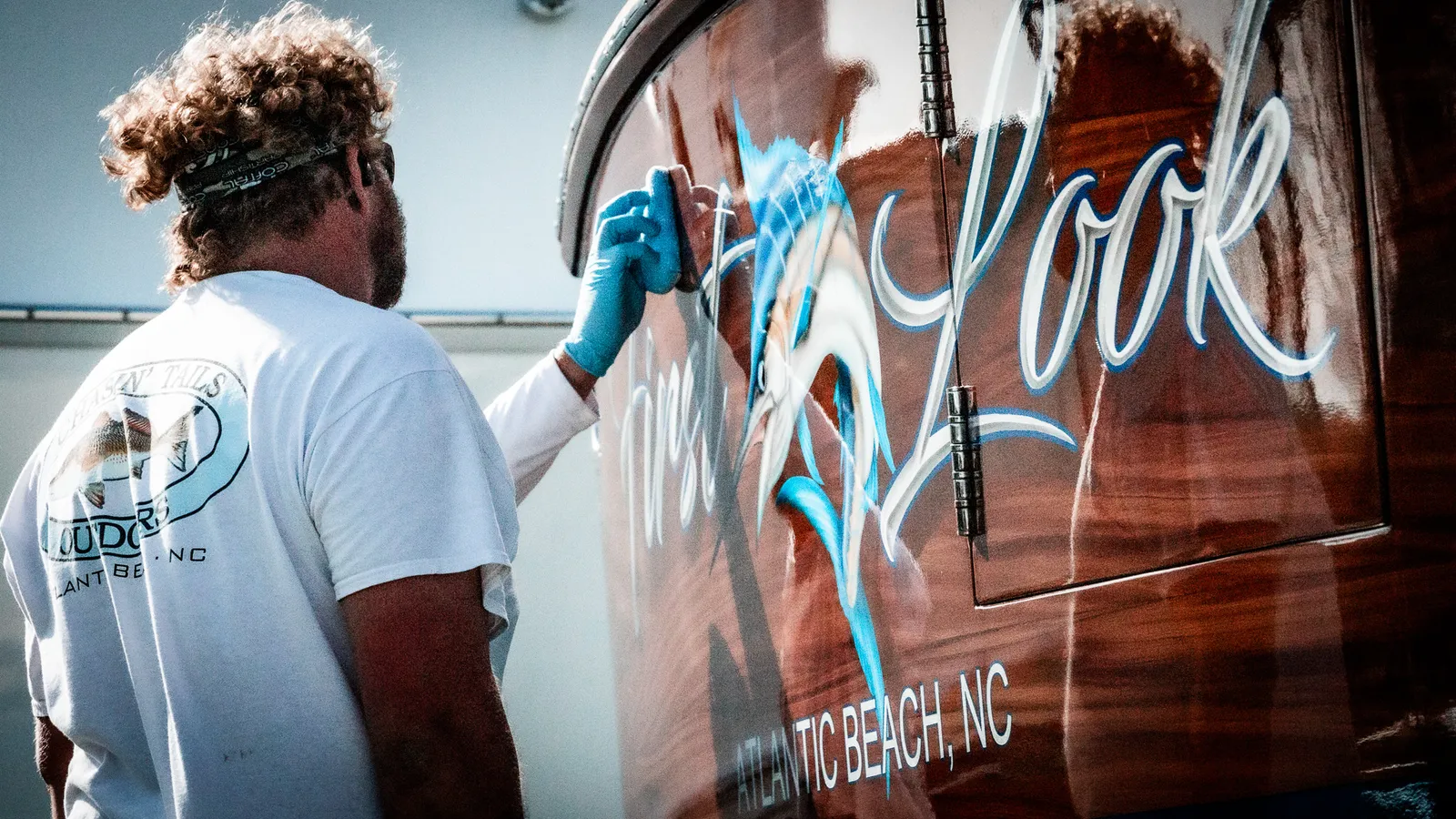 Detailer hand-applying marine ceramic coating to the glossy transom of a sportfishing boat