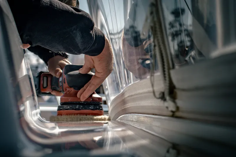 Detailer machine-polishing the cabin gelcoat of a sportfishing boat to a high gloss